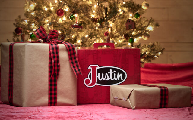 Caja de botas de Justin debajo de un árbol de Navidad con otros regalos.